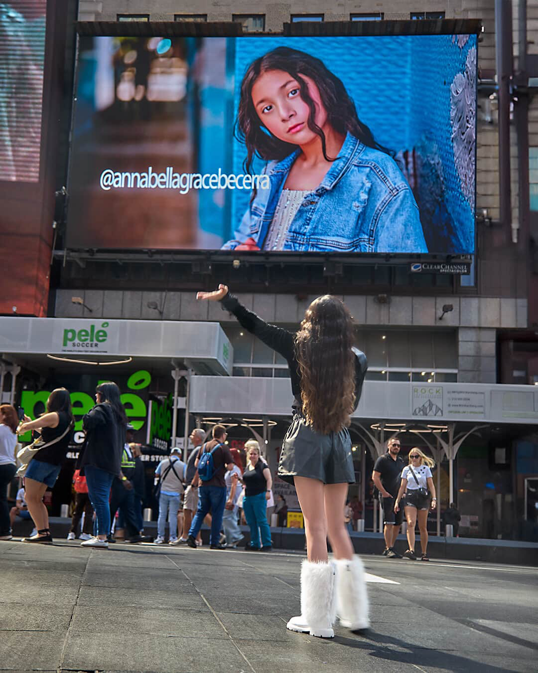 Young fashion model photographed in front of her Times Square billboard feature
