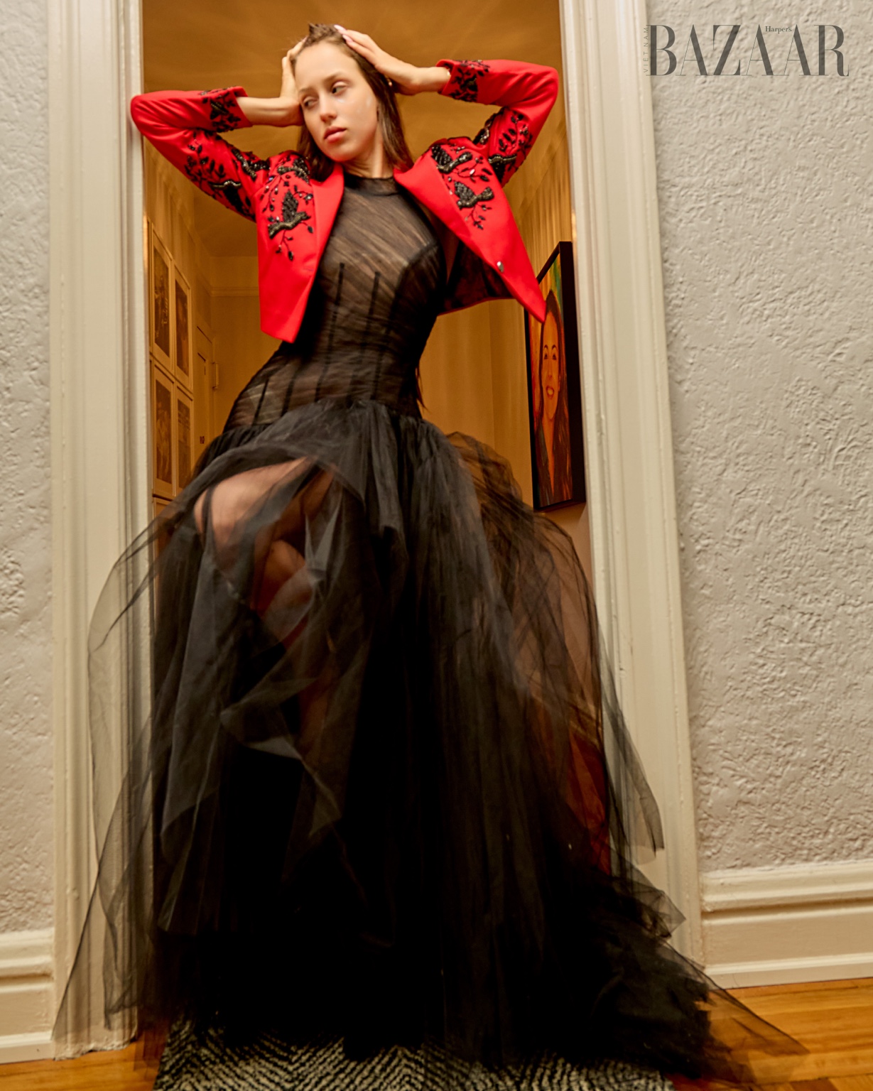 Model in a red embroidered jacket over a black tulle gown, photographed for Harper’s Bazaar