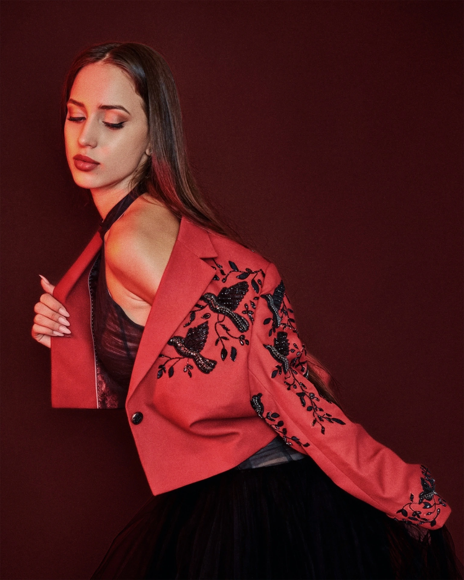 Model in a red embroidered jacket against a dark backdrop