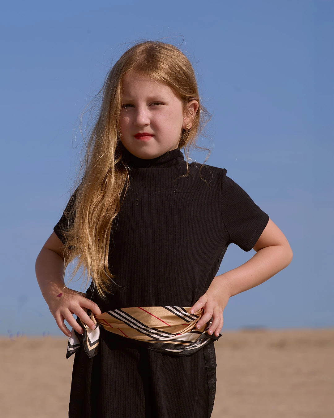 Young model in a black outfit and patterned scarf at the beach
