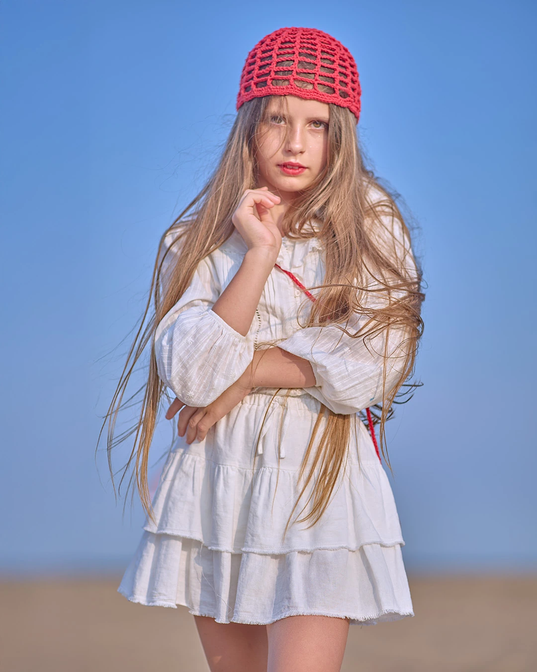 Young model in a white dress and red knit cap